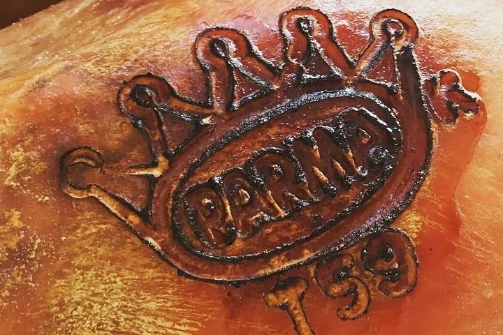 Die Herzogskrone und das Wort PARMA in die Schwarte eines Schinkens eingebrannt, darunter eine Nummer